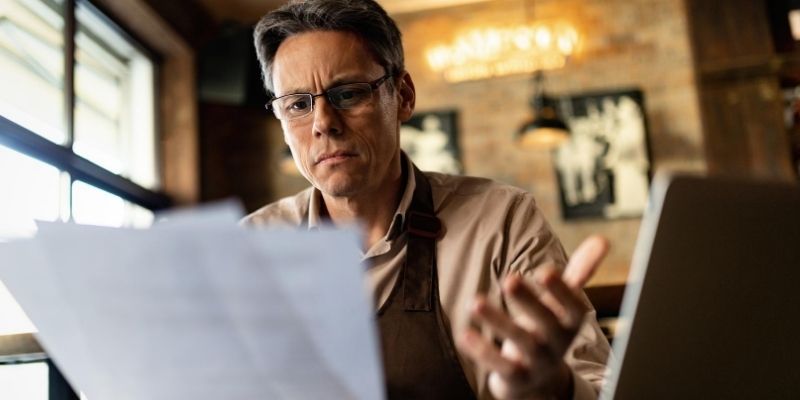 Confused male small business owner reading loan paperwork