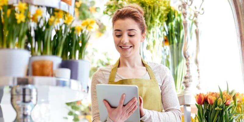 Female business owner using tablet to apply for small business funding in a flower shop