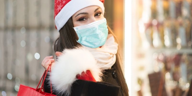 female shopper wearing face mask buying gifts holiday shopping for christmas festive season 2020
