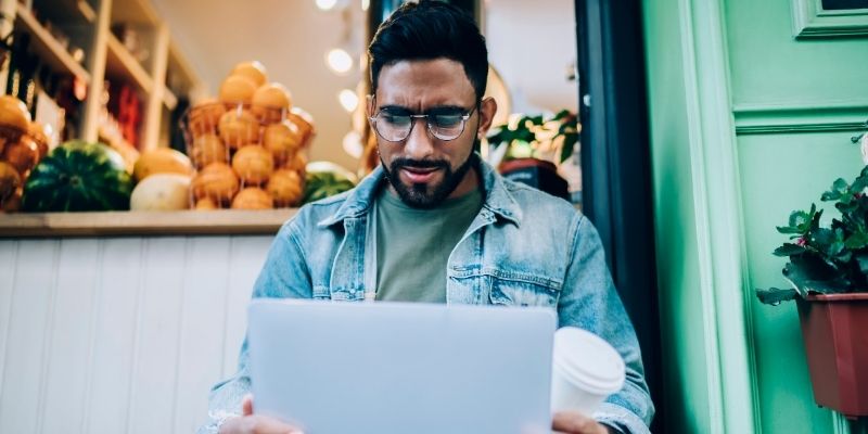 confused business owner looking at laptop outside small business
