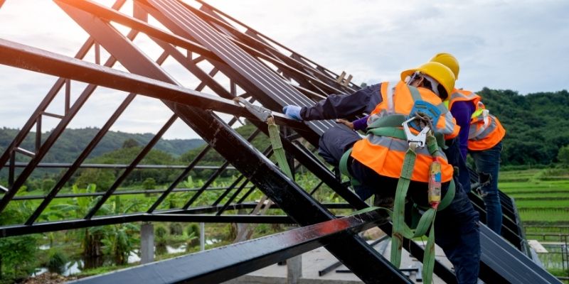 Two construction workers working on roof beams outdoors