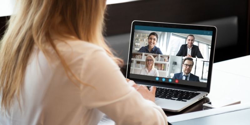 female office worker working remotely having zoom meeting with colleagues on laptop