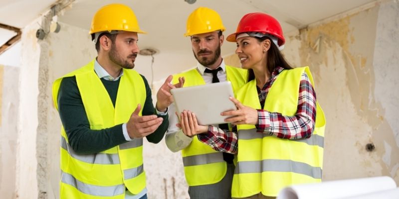 male and female construction professionals discuss blueprints at construction site