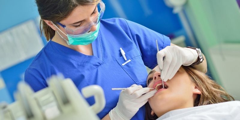 female dentist cleaning patients teeth