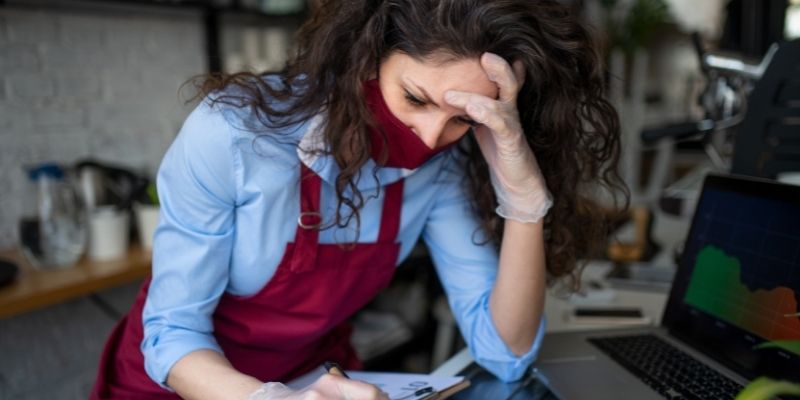 frustrated female business owner in cafe restaurant researching funding options