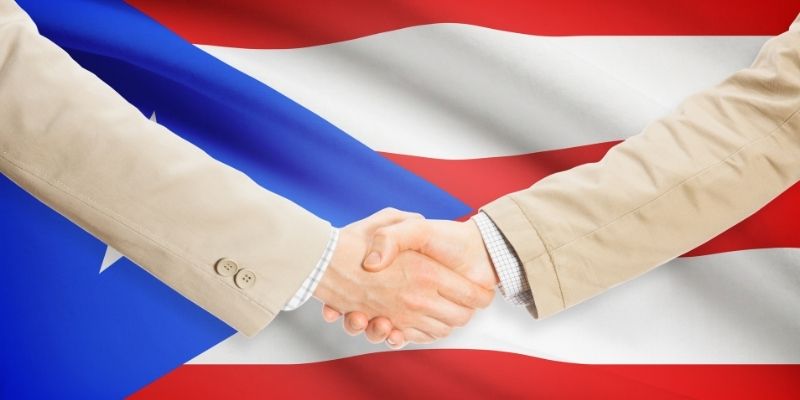 two hands shaking in front of puerto rico flag