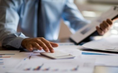 accountant calculating numbers with clip board and graphs on desk