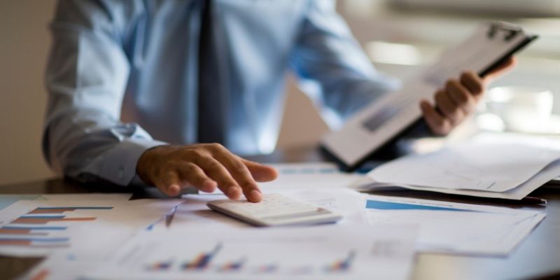 accountant calculating numbers with clip board and graphs on desk