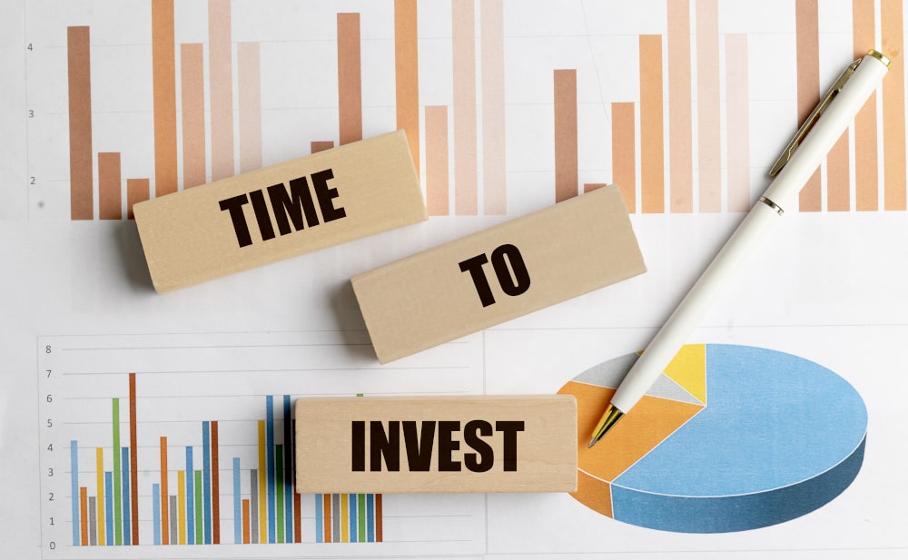 When is the right time to invest in your business? When is the right time to invest in your business: Wooden blocks with words time to invest on financial charts with white pen and pie graph loan form on desk with keyboard, eyeglasses and pen